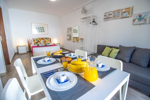 A modern, well-lit dining area with a table set for breakfast, including plates, cutlery, and a pitcher of orange juice. - Vilamoura Golf Studio With Pool (Loulé)