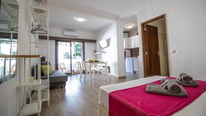 A hotel room with a bed, a desk, a chair, a TV, and a kitchenette. - Vilamoura Golf Studio With Pool (Loulé)