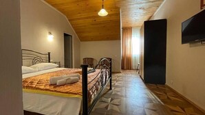 A bedroom with a bed, wooden ceiling, and a television on the wall. - Hotel Laguna (Ureki)