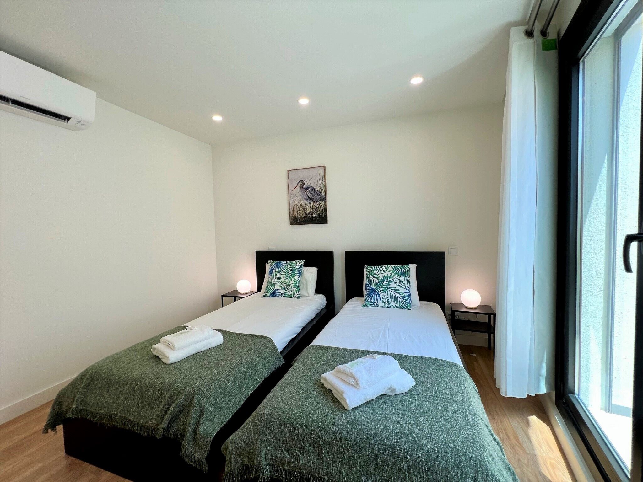 Ein Hotelzimmer mit zwei Betten, einem Bild an der Wand und einem Fenster mit Vorhängen.