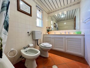 A bathroom with a bidet, toilet, and a large mirror above the sink.