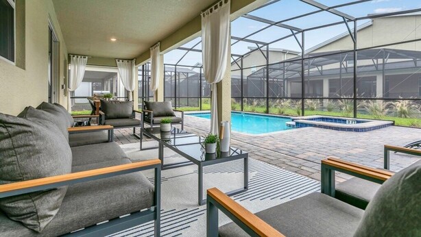 A covered outdoor area with a pool, seating, and a view of the backyard. - The Best Value by All Vacation (Kissimmee)