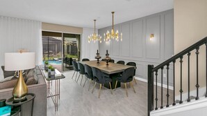 A dining area with a wooden table, black chairs, and a chandelier. - The Best Value by All Vacation (Kissimmee)