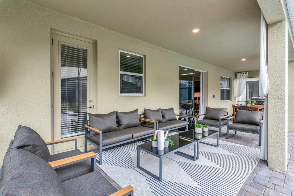 A covered outdoor seating area with a sofa, chairs, and a coffee table.