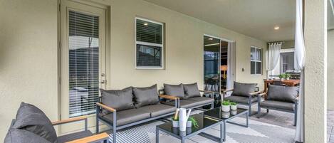A covered outdoor seating area with a sofa, chairs, and a coffee table.