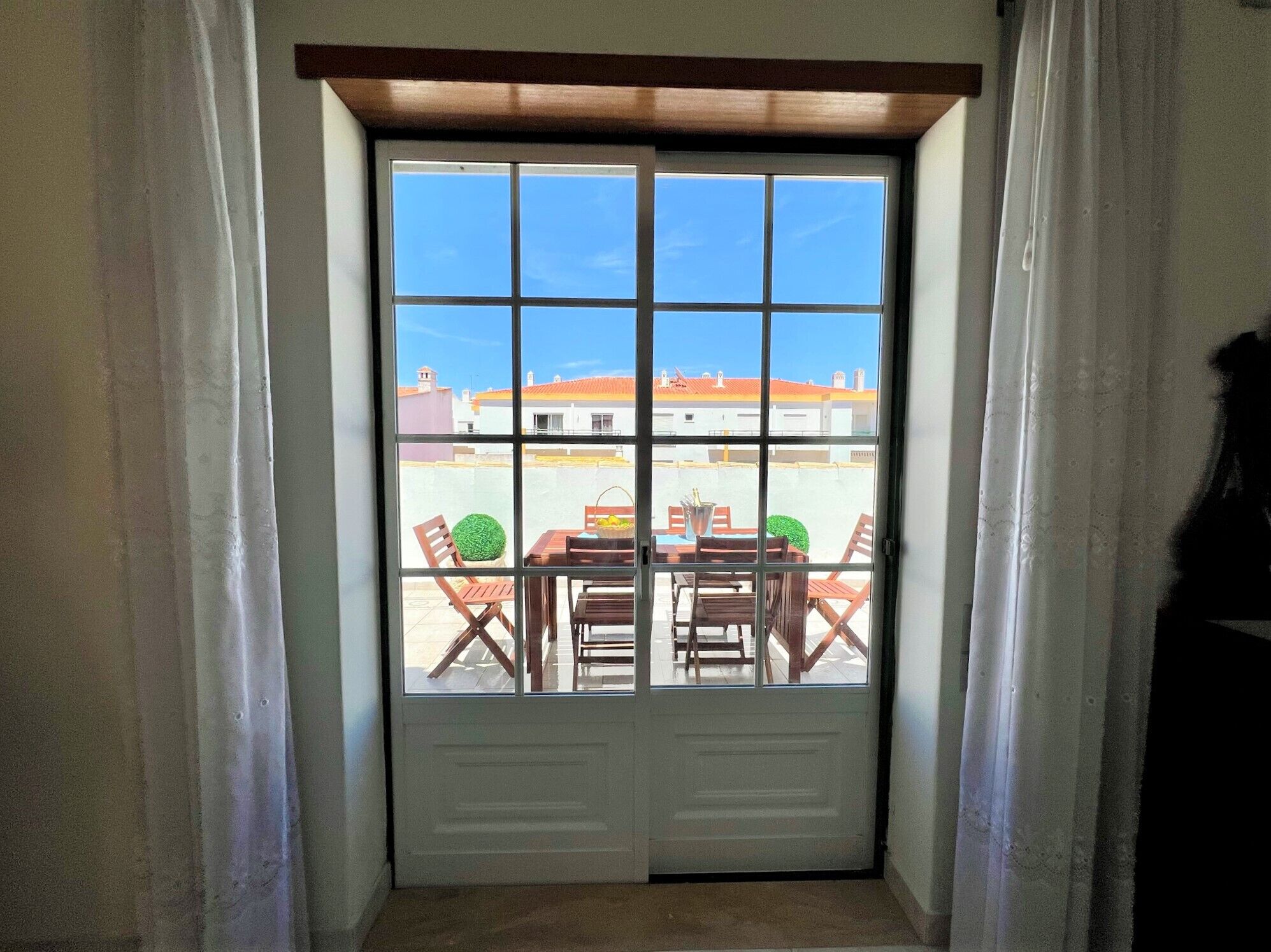 A door with a view of an outdoor patio area with a table and chairs.