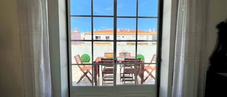 A door with a view of an outdoor patio area with a table and chairs.