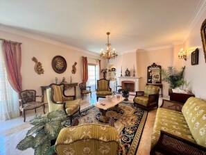 Ein traditionelles Wohnzimmer mit Kamin, aufwendigen Möbeln und einer Chandelüster.