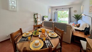 A dining area with a round table set for breakfast, including plates of food, glasses, and cutlery. - Casa D`sul by Homing (Tavira)