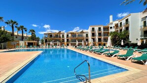A swimming pool with lounge chairs and a building with balconies in the background. - Casa D`sul by Homing (Tavira)