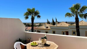 A balcony with a table set for two, a bottle of champagne, and a bowl of fruit. - Casa D`sul by Homing (Tavira)