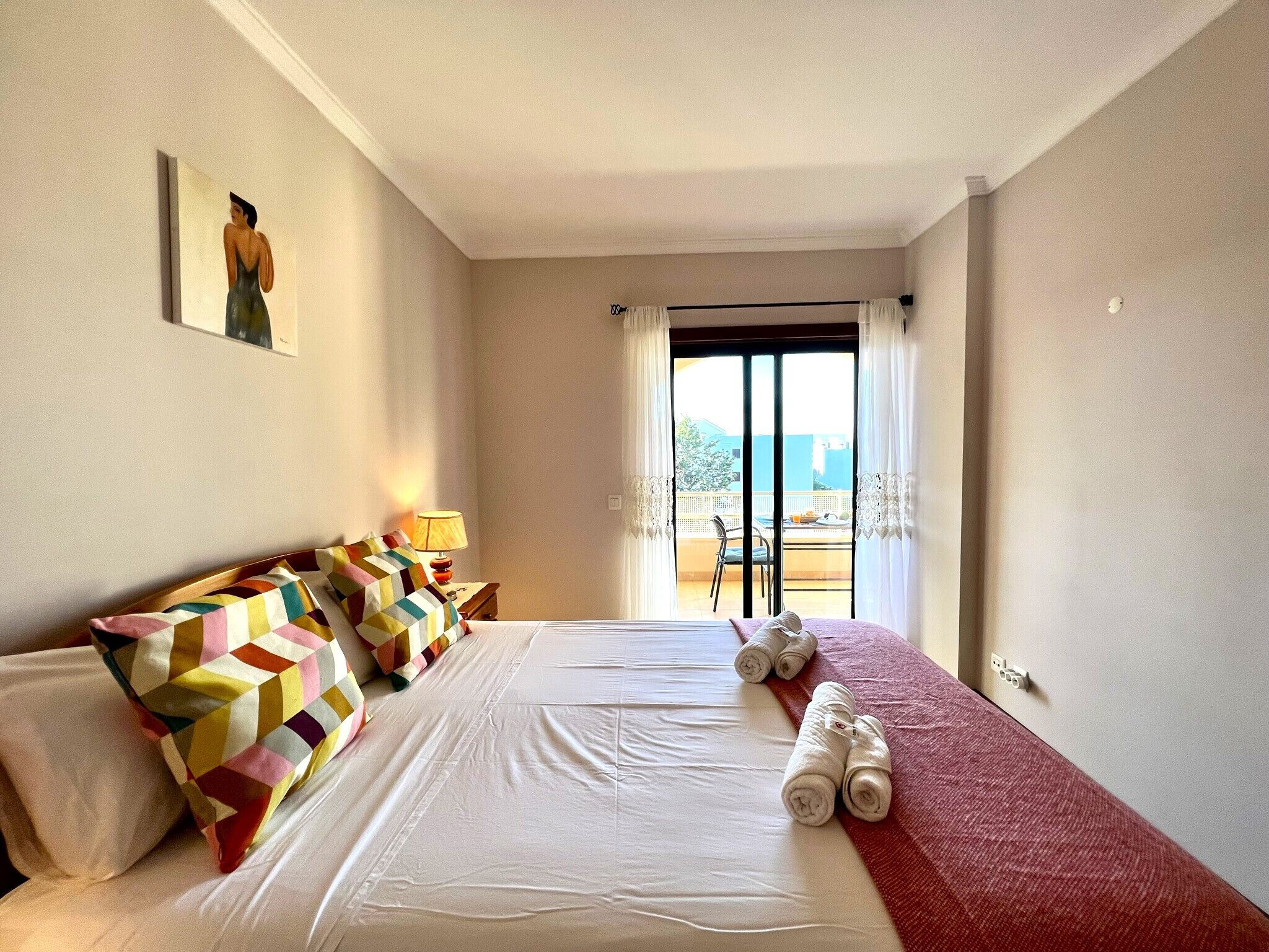 Une chambre d’hôtel avec un lit, des oreillers, une table de chevet, une lampe et une vue par la fenêtre.