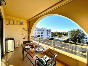 A balcony with a table set for breakfast, a view of buildings, and a yellow railing. - Albufeira Salgados Beach 3 by Homing (Albufeira)