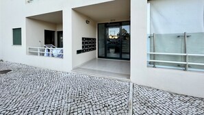 A modern building with a tiled entrance, a glass door, and a metal railing. - Albufeira Salgados Beach 3 by Homing (Albufeira)