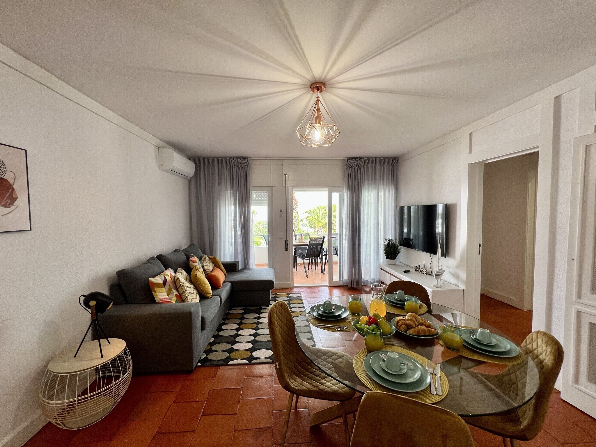 A modern living room with a sofa, dining table, and a TV.