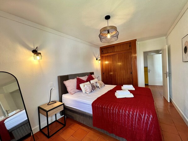 A hotel room with a bed, bedside table, and a mirror.