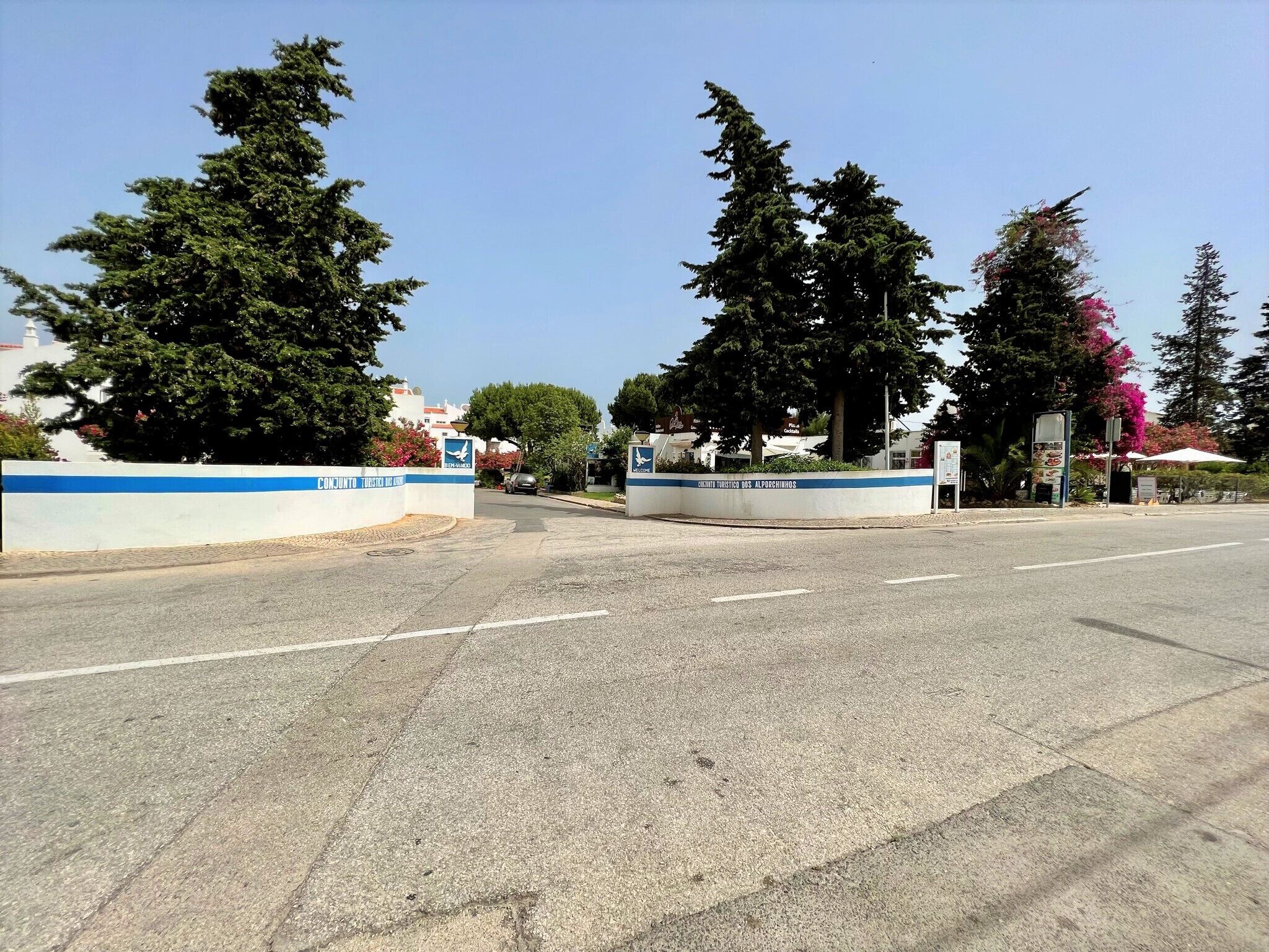 A road leading to a building with a blue and white sign.