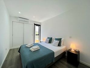 Ein modernes Schlafzimmer mit einem Bett, Nachttischen und einer Klimaanlage.