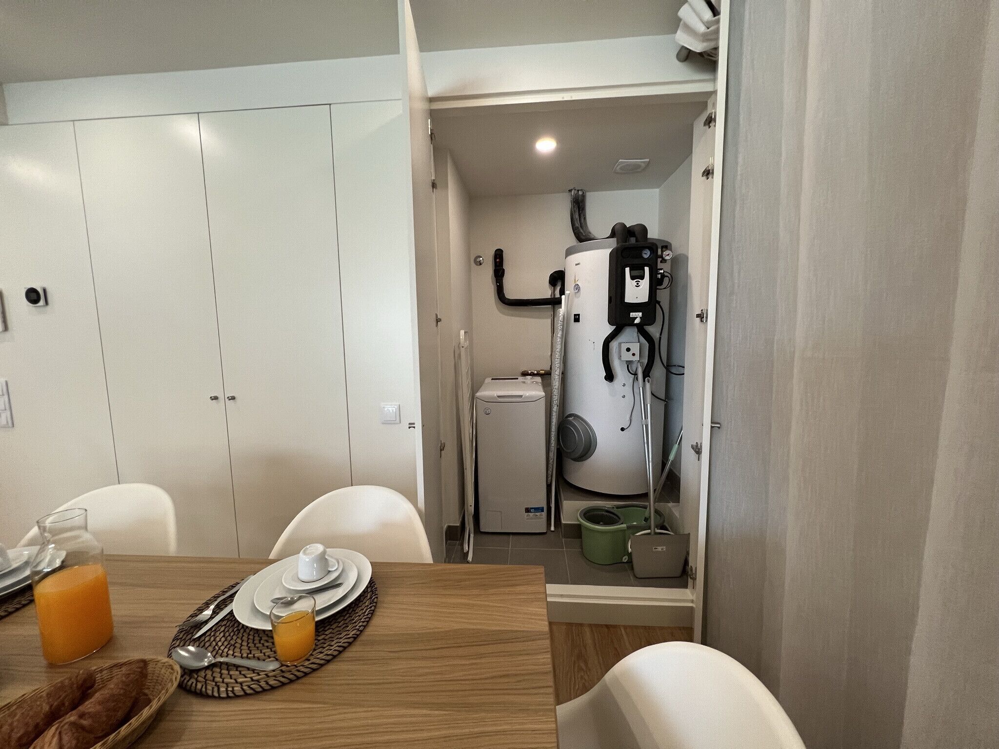 Una cocina compacta con calentador de agua, un refrigerador pequeño y una zona de comedor con una mesa dispuesta para dos.