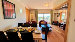 A modern hotel room with a dining area, a living area with a sofa and armchairs, and a balcony with a view. - Albufeira Modern 2 by Homing (Albufeira)