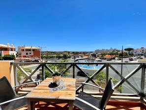 Eine Terrasse mit Tisch und Stühlen, einer Champagnerflasche und Blick auf die Stadtlandschaft.