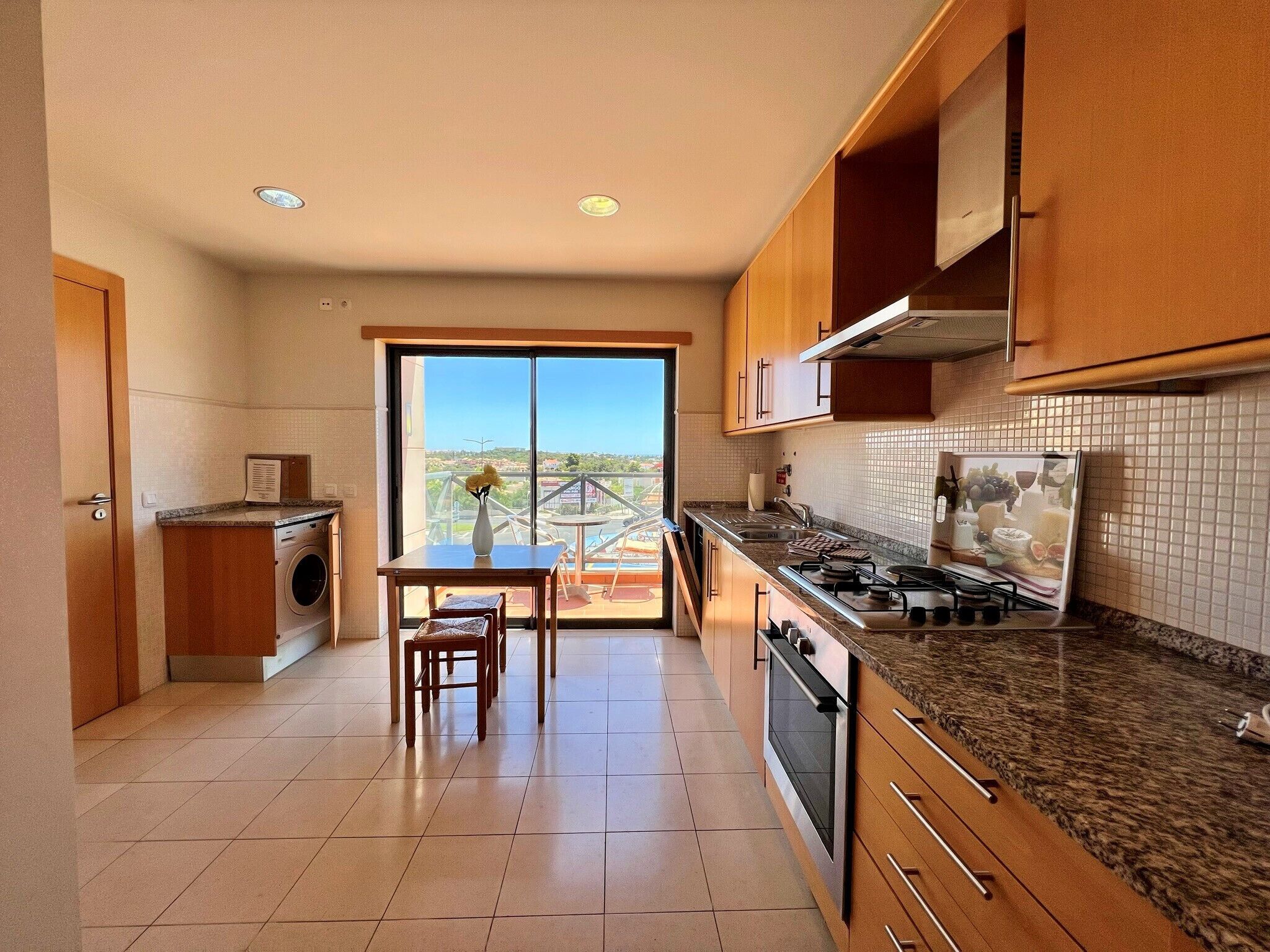A modern kitchen with a dining area, large windows, and a view of the city.