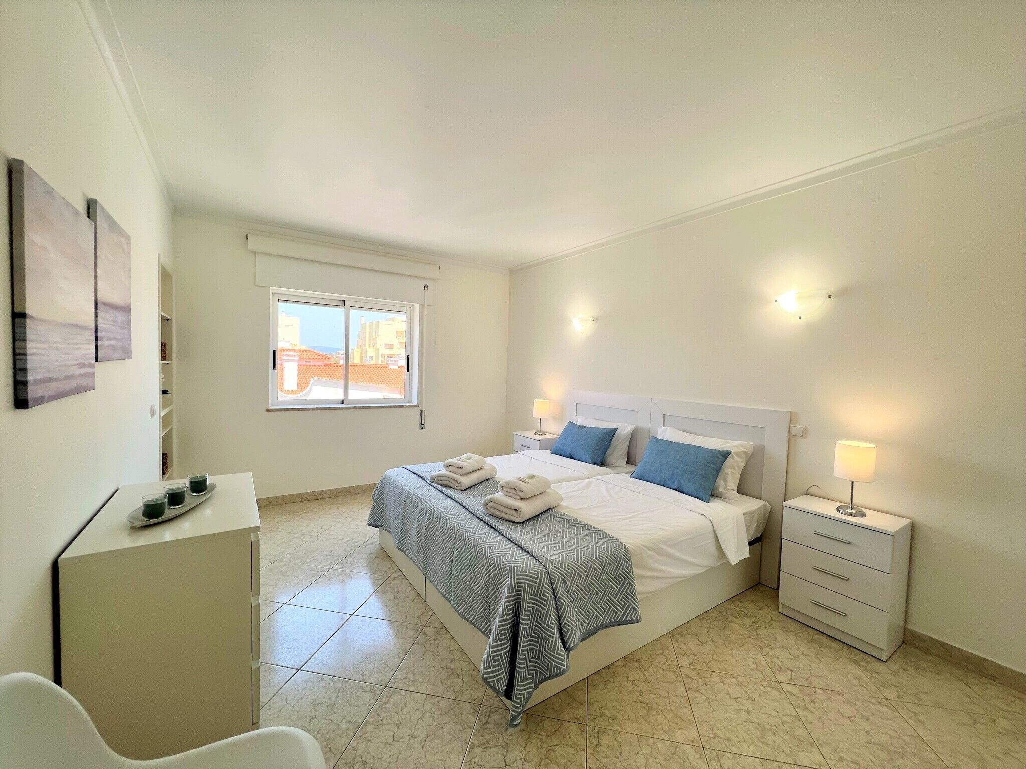A bedroom with a bed, bedside tables, a desk, and a chair.