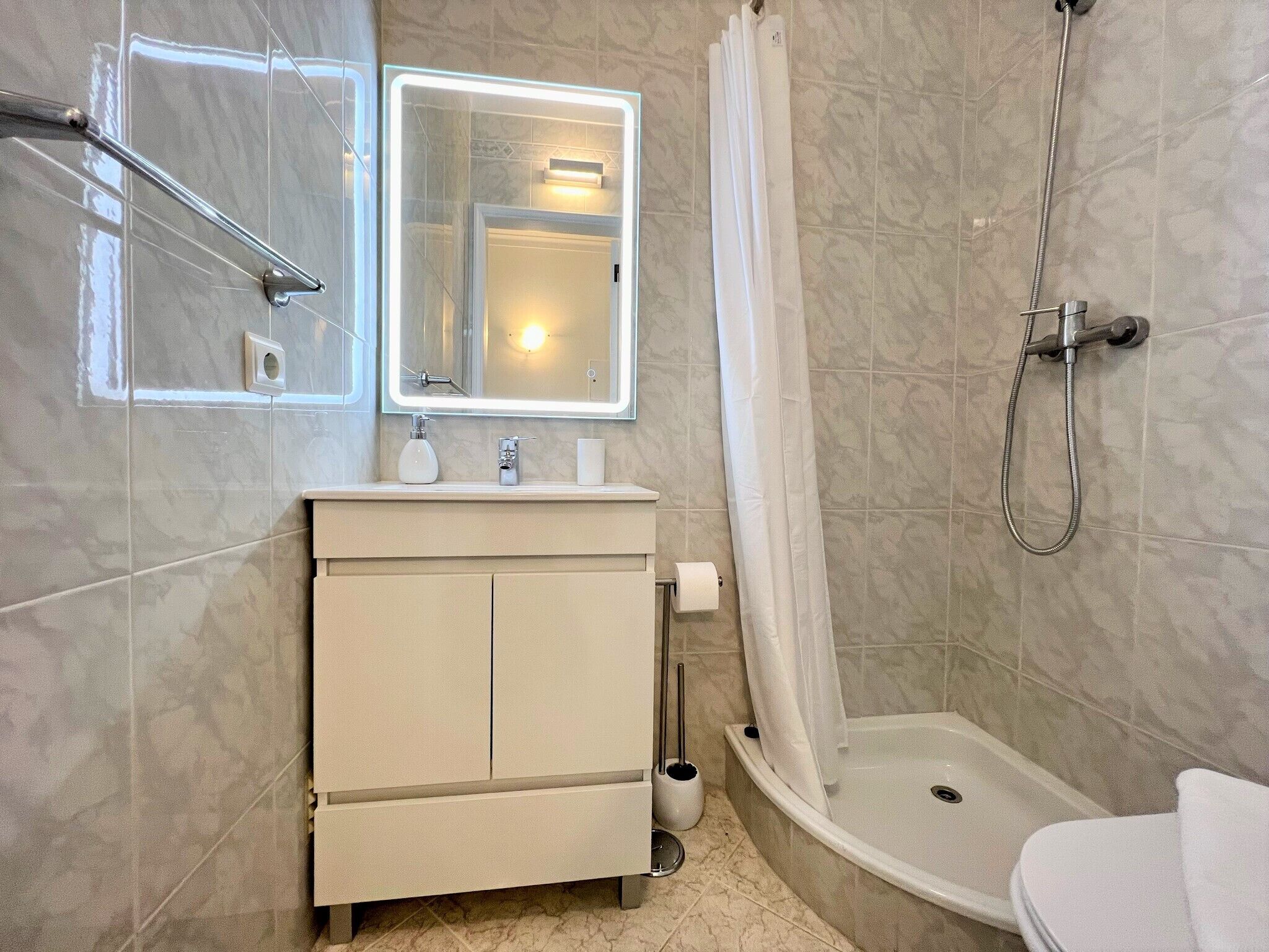 A modern bathroom with a vanity, a shower, and a toilet.
