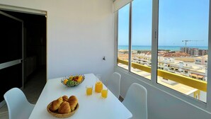A balcony with a table set for breakfast, a fruit bowl, and two glasses of orange juice. - Quarteira Panoramic View by Homing (Loulé)
