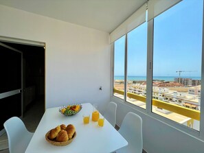 Ein Balkon mit einem Frühstückstisch, einer Obstschale und zwei Gläsern Orangensaft.