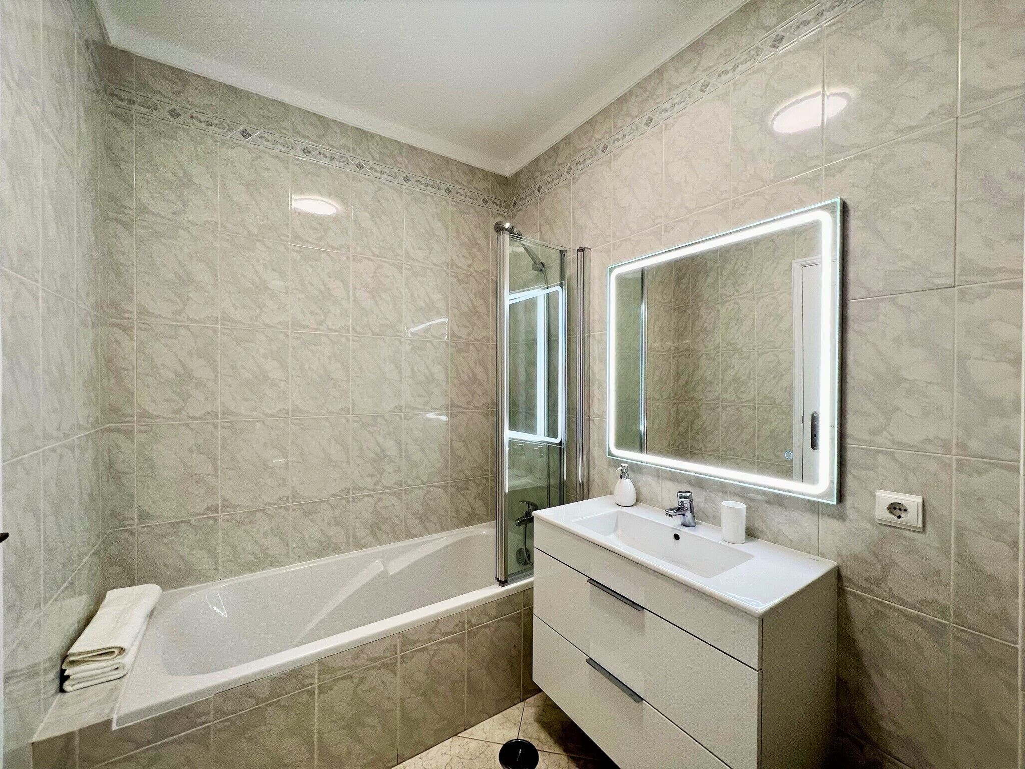 Un baño moderno con bañera, tocador y un espejo grande.