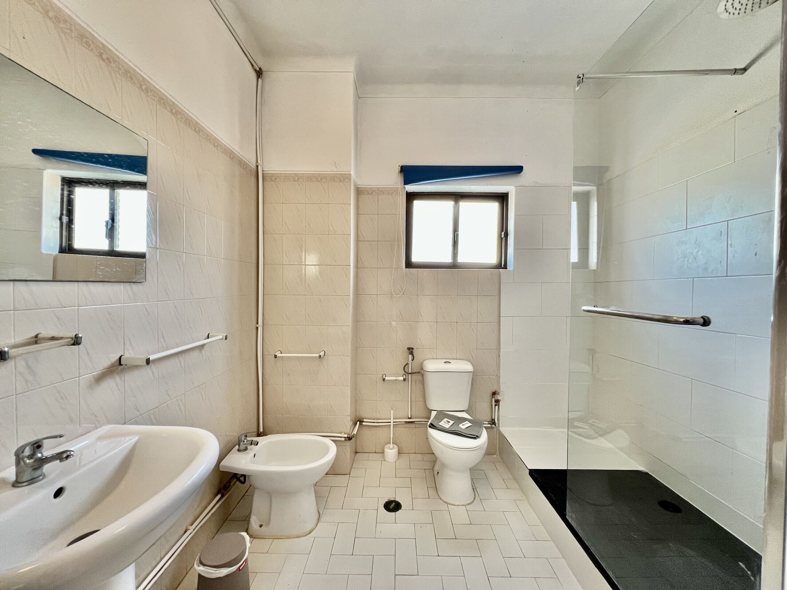 A bathroom with a sink, bidet, toilet, and shower.