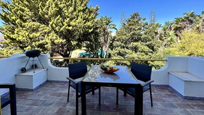 A patio with a table and chairs, a barbecue grill, and a view of a pool and trees. - Quarteira Stylish With Pool by Homing (Loulé)
