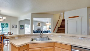 A kitchen with wooden cabinets, a stainless steel sink, and a dishwasher. There is a staircase leading to another level. - Pet-Friendly Meridian Vacation Rental w/ Fire Pit! (Meridian)