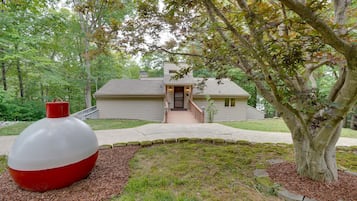 Stunning two-story home with a welcoming front entrance and covered porch, set amidst a serene wooded area.
