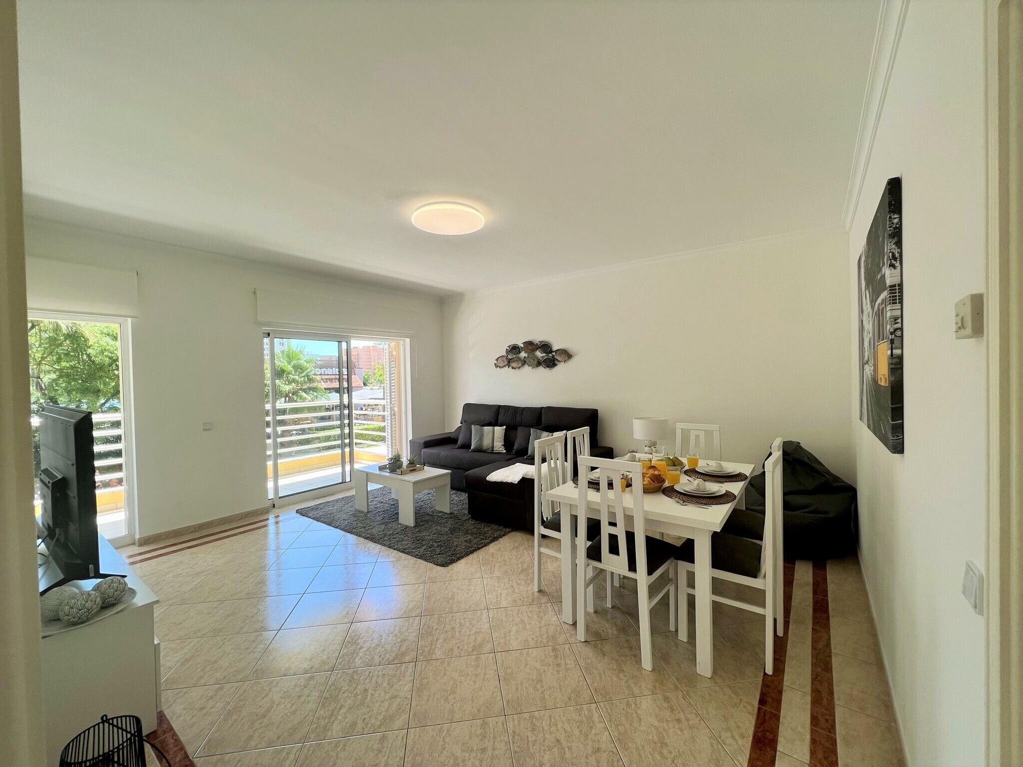 A living room with a sofa, dining table, chairs, and a TV.