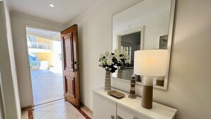 A hallway with a white console table, a mirror, and a door leading to an outdoor area. - Vilamoura Central 2 With Pool by Homing (Loulé)