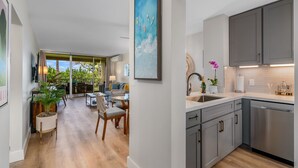 A modern kitchen with grey cabinets, a stainless steel dishwasher, and a large window.