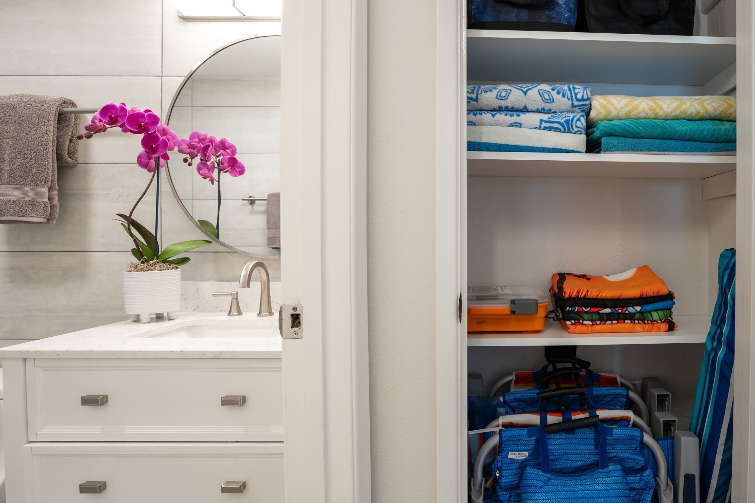 A bathroom with a white sink, a potted orchid, and a towel rack.