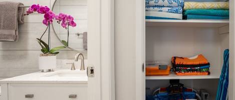 A bathroom with a white sink, a potted orchid, and a towel rack.