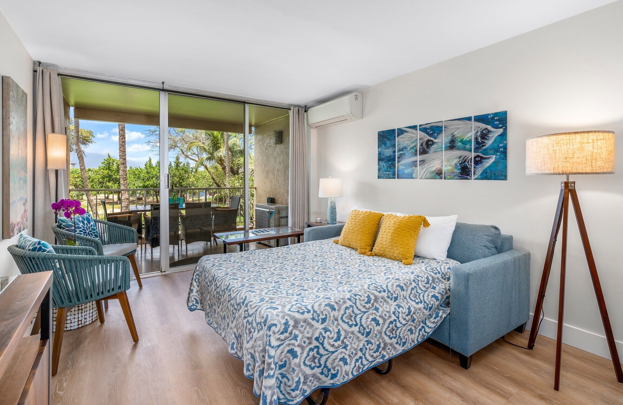 Une chambre d’hôtel comprenant un lit, un canapé, un bureau et un balcon avec une table et des chaises.
