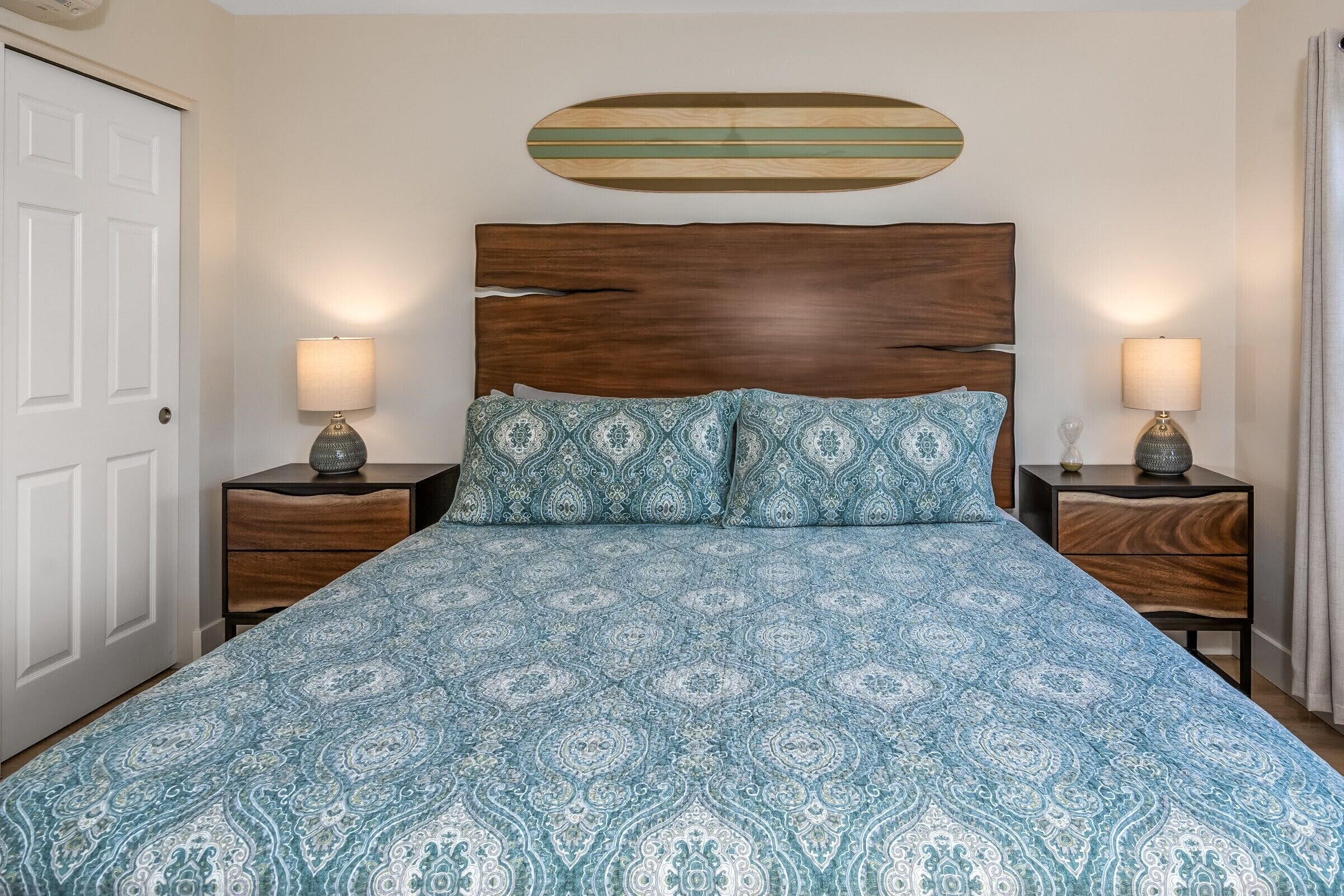 Una camera da letto con testiera in legno, biancheria a motivi decorativi, due comodini con lampade e un elemento decorativo in legno sopra il letto.