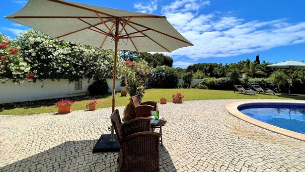 An outdoor patio with a pool, wicker furniture, and potted plants. - Albufeira Balaia Villa With Private Pool (Albufeira)