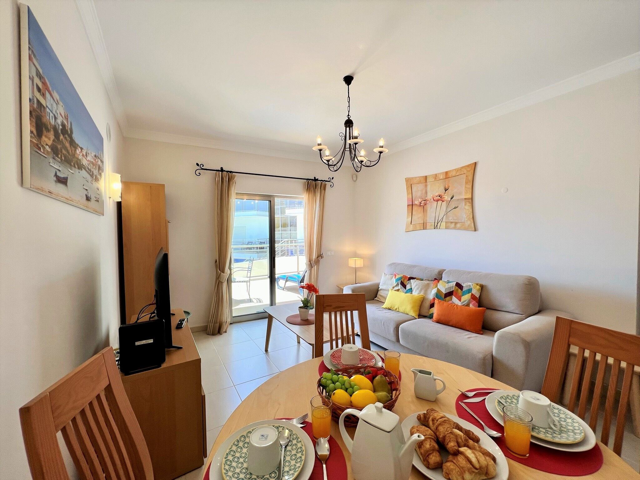 Un área de comedor con una mesa lista para el desayuno, un sofá y un balcón con vistas.
