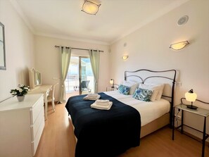 Ein Hotelzimmer mit Bett, Nachttischen, einem Schreibtisch, einem Stuhl und Blick auf den Balkon.