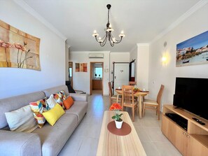 Ein modernes Wohnzimmer mit Sofa, Couchtisch, Esstisch und Fernseher.