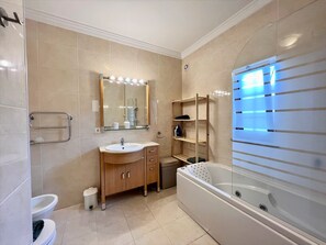 Un baño moderno con tocador, lavamanos, espejo y ducha a ras de suelo.