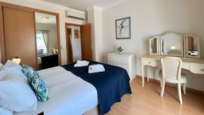 Een hotelkamer met een bed, een bureau, een stoel, een kast en een schilderij aan de muur.