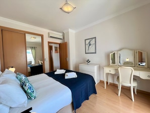Ein Hotelzimmer mit Bett, Schreibtisch, Stuhl, Kommode und einem Gemälde an der Wand.