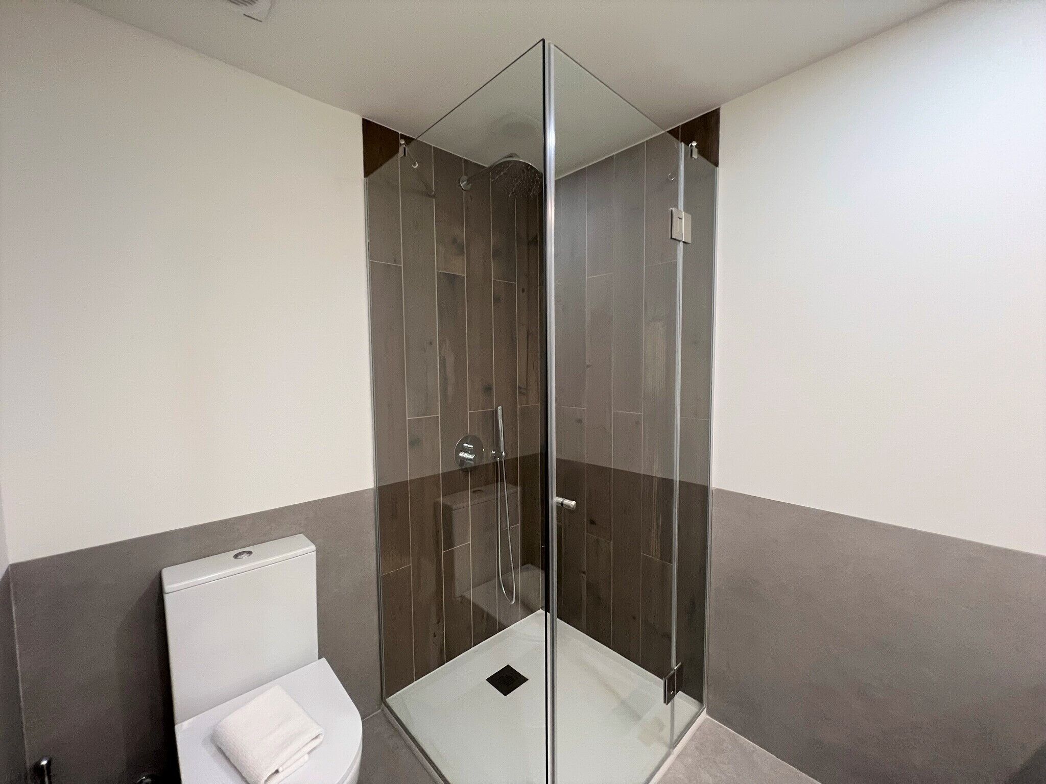 Ein modernes Badezimmer mit einer ein Glasfachwerk-Dusche, einer weißen Toilette und einem Handtuch auf der Sitzfläche.
